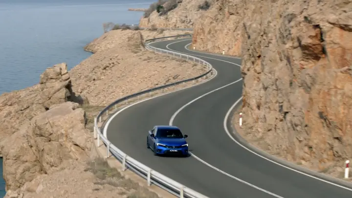 Hybrydowa Honda Civic jadąca nadbrzeżną drogą.