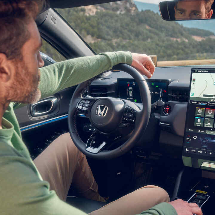 Mężczyzna jadący Hondą e:Ny1 i używający nawigacji na cyfrowym wyświetlaczu kierowcy.