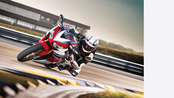 Widok 3/4 przodu Fireblade'a z kierowcą, w zakręcie na torze. Skierowany w prawo.