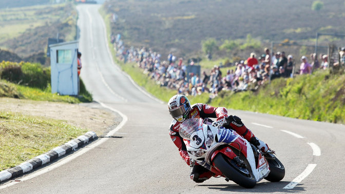Honda Fireblade - widok przedstawiający motocykl z kierowcą na torze wyścigowym z przedniej lewej perspektywy.