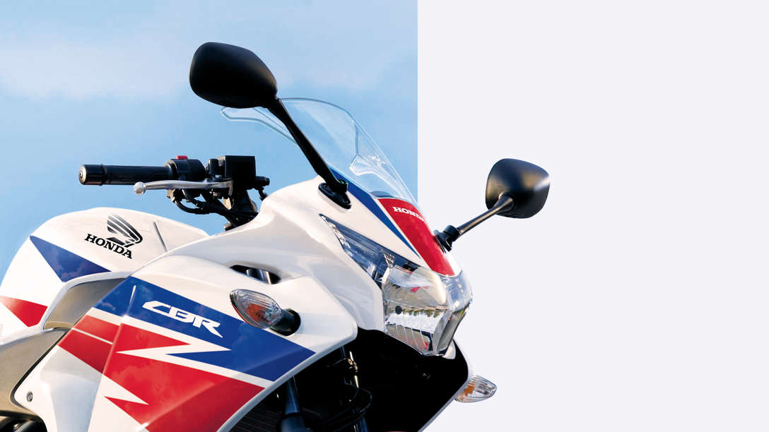 Zbliżenie motocykla z profilu; reflektor, kierownica i szyba. Widok z prawej strony