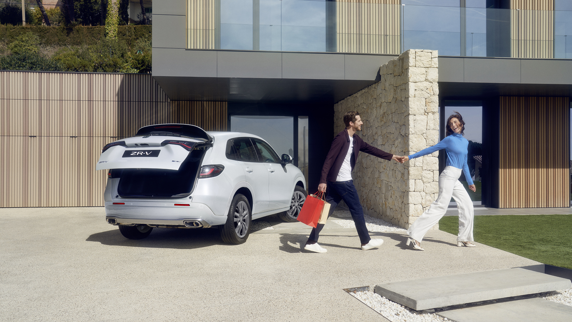 Biała Honda ZR-V na podjeździe z pokrywą bagażnika sterowaną elektrycznie