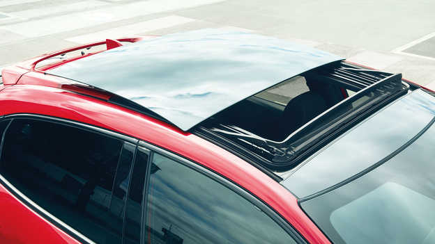 Ujęcie otwieranego szklanego dachu w czerwonej Hondzie Civic.