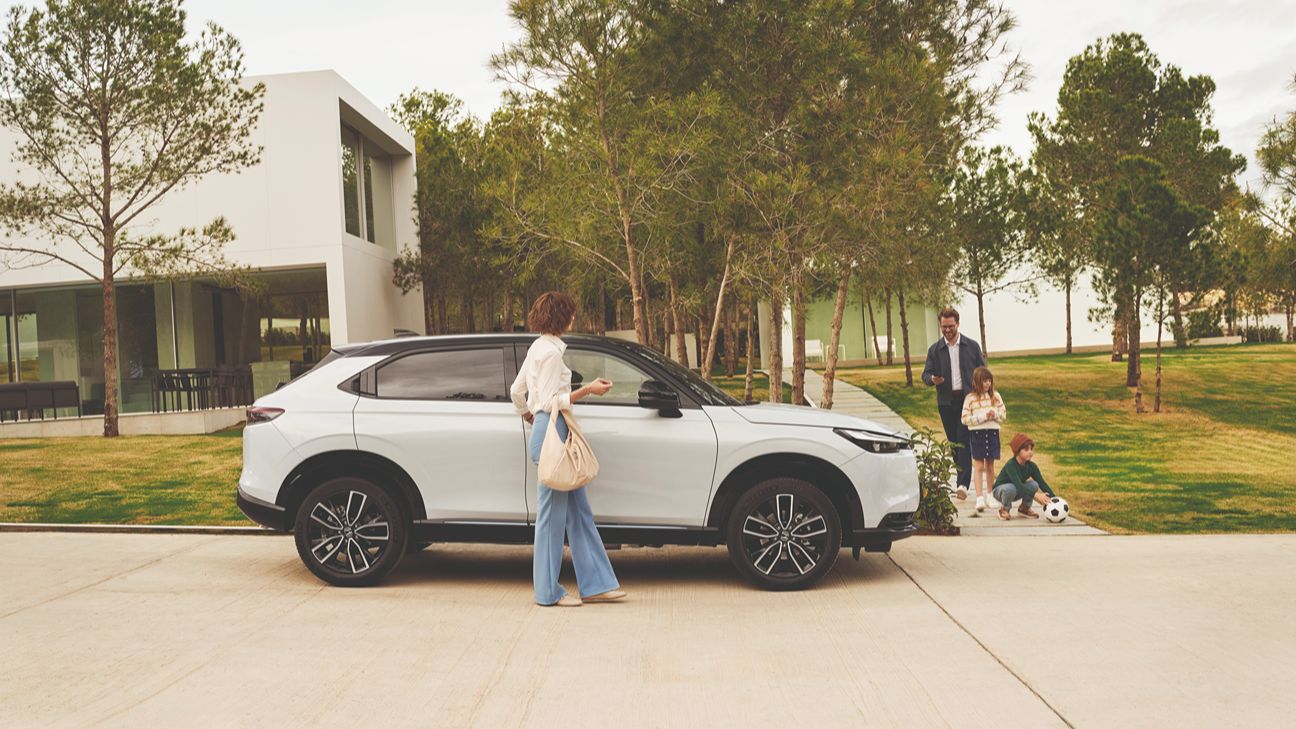 Czteroosobowa rodzina wsiadająca do hybrydowego SUV-a Hondy