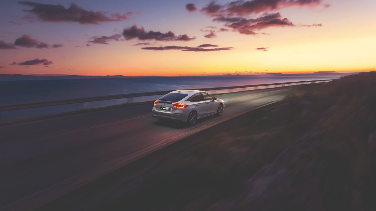 Biała Honda Civic jadąca o zachodzie słońca