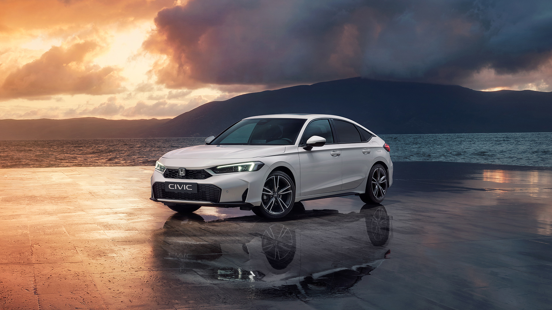 Civic Hybrid zaparkowany obok oceanu o zachodzie słońca.