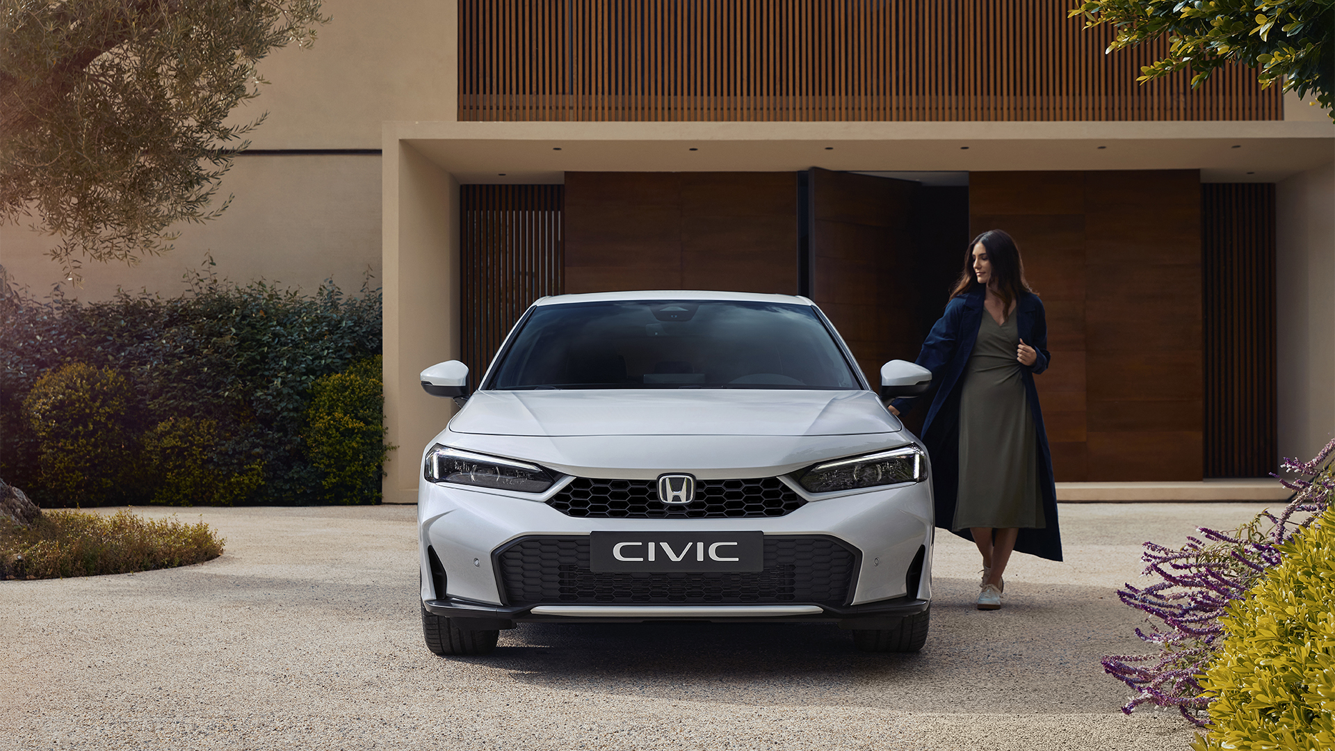 Przednie ujęcie modelu Civic Hybrid z kobietą otwierającą drzwi.