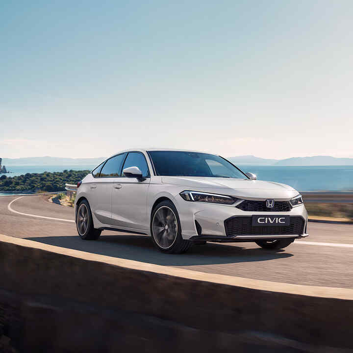 Nowa Honda Civic e:HEV jadąca na drodze, widoczna od boku
