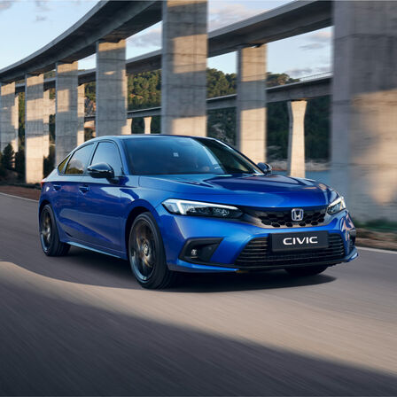 Honda Civic e:HEV hatchback jadąca drogą - widok z przedniej perspektywy.
