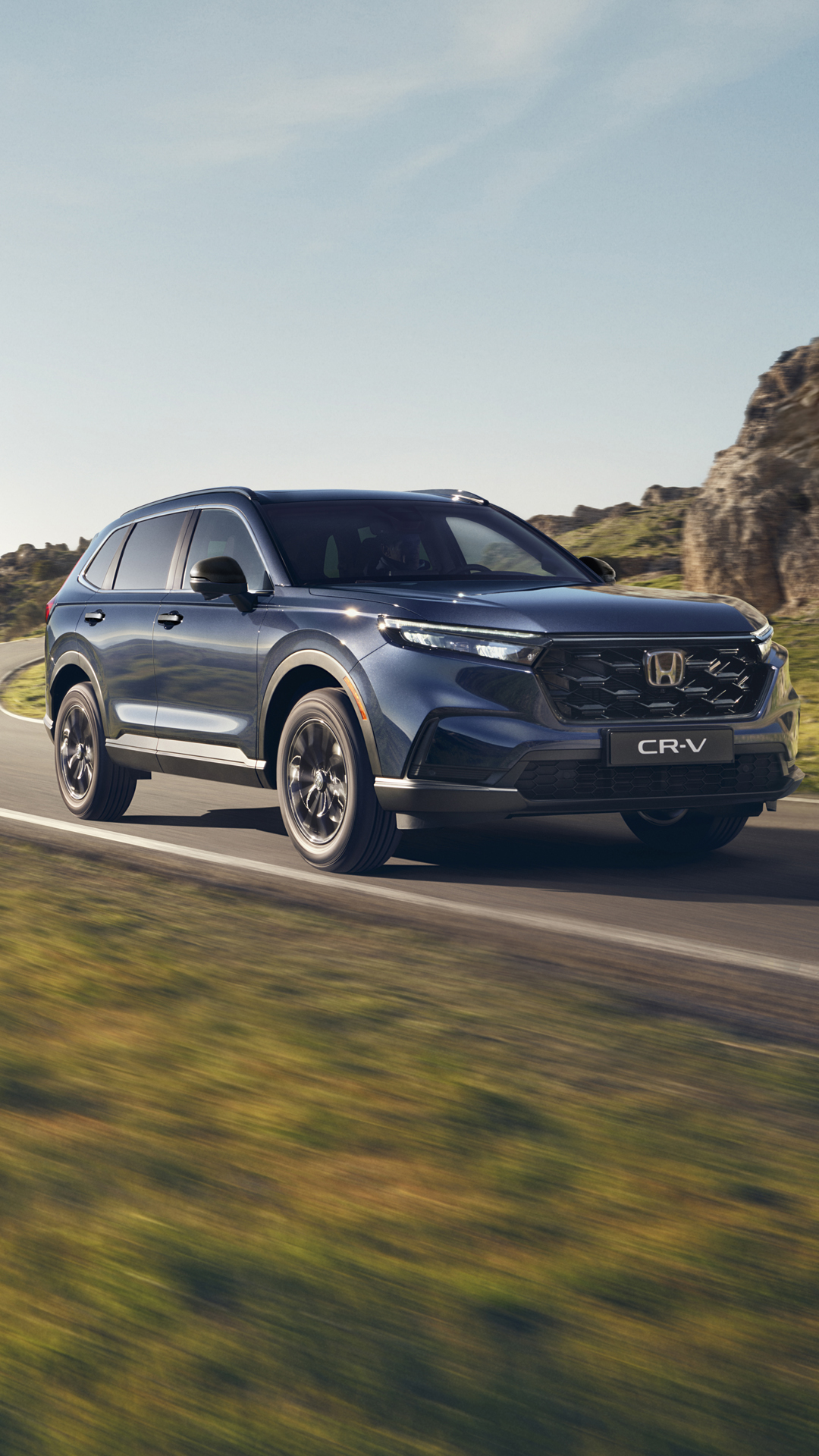 SUV CR-V z napędem Plug in Hybrid jadący drogą w górzystym terenie.