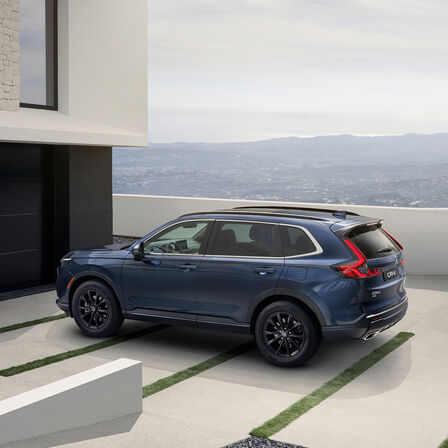 Side view of Honda CR-V Full Hybrid SUV car parked in car park overlooking mountains location.
