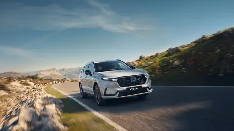 Hybrydowy SUV CR-V - widok z przodu na samochód jadący w górzystym terenie.