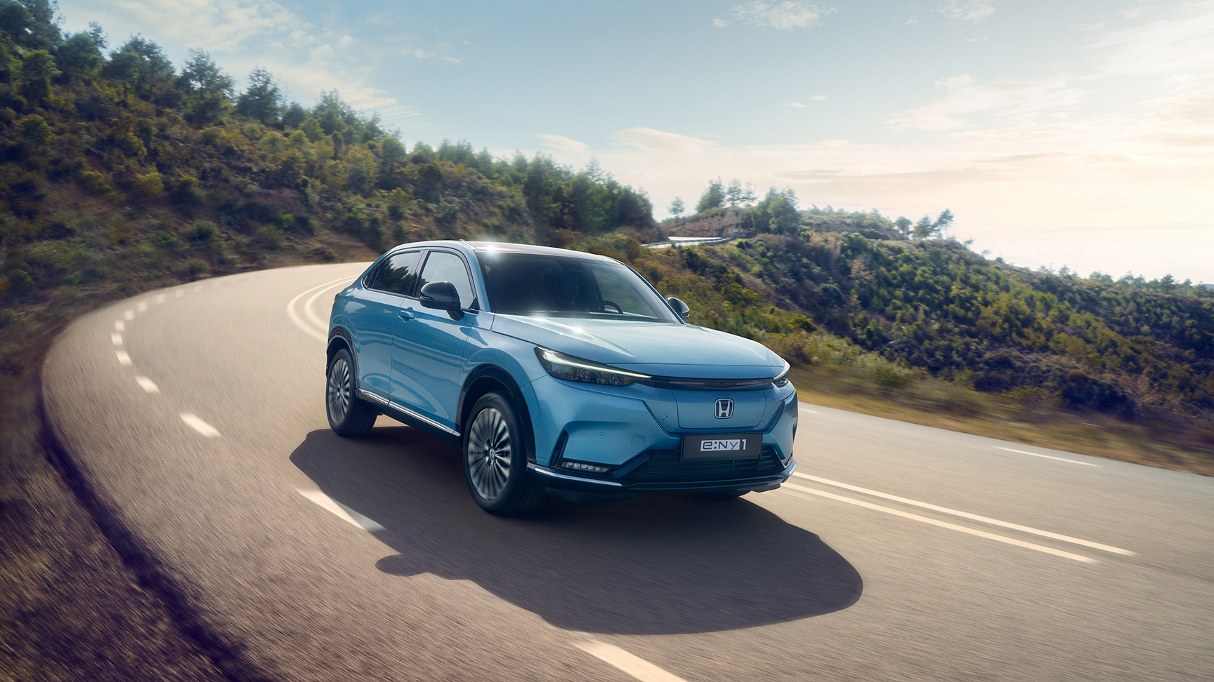 Widok z przodu na Hondę e:Ny1 jadąca drogą poza miastem.