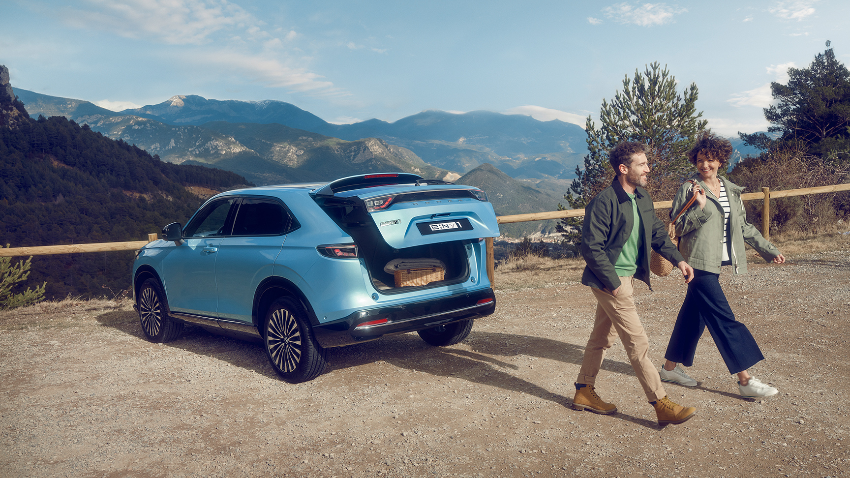 Widok z tyłu na Hondę e:Ny1 w górskiej scenerii z oddalającą się parą.