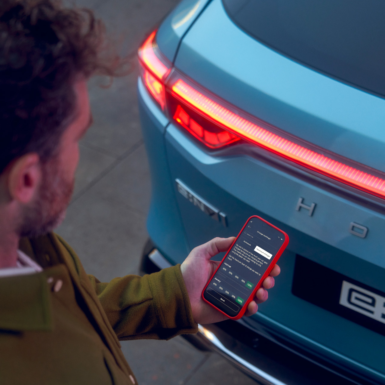 Mężczyzna stojący obok Hondy e:Ny1 i patrzący w okno aplikacji My Honda+