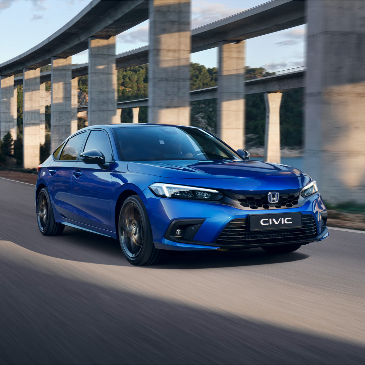 Hybrydowa Honda Civic w kolorze niebieskim jadąca w górskiej scenerii.