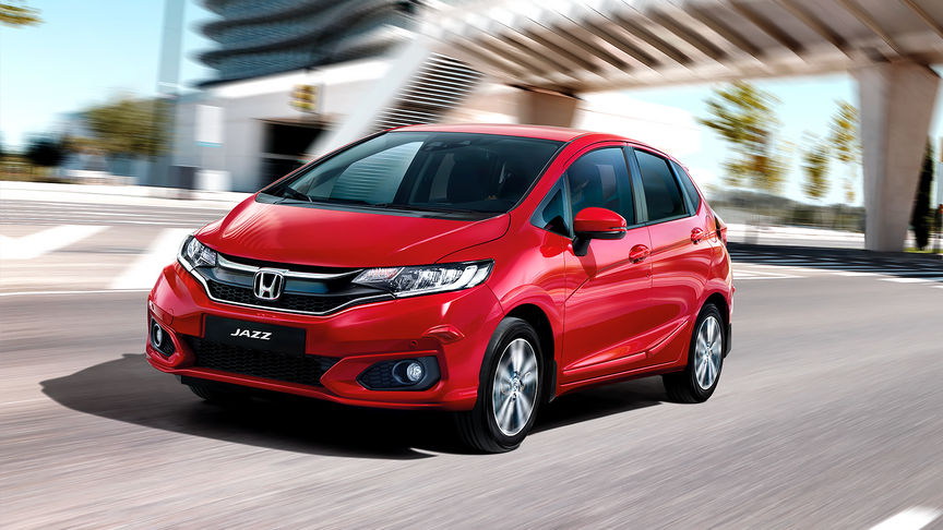 Honda Jazz z Pakietem Praktycznym z przodu w krajobrazie miejskim.
