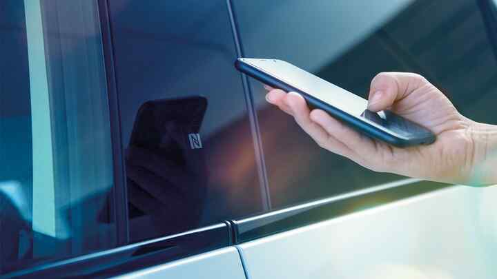 Zbliżenie na osobę używającą aplikacji My Honda+ na telefonie poza samochodem