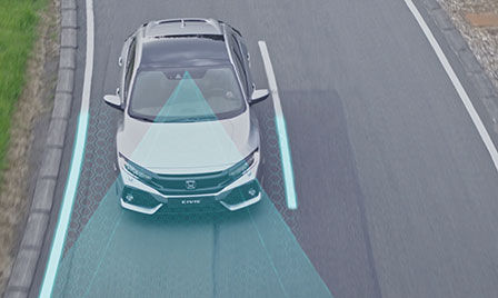Honda Sensing — zdjęcie pojazdu na drodze ilustrujące system utrzymywania na pasie ruchu oraz system ograniczający skutki kolizji.
