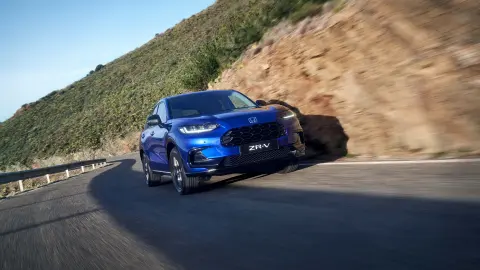 Hybrydowy SUV Honda ZR-V jadący drogą w górzystym terenie.
