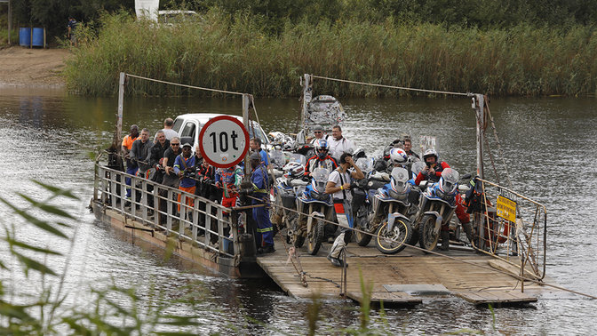 Motocykle przeprawiane łodzią przez rzekę.