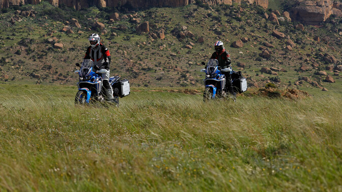 dwóch uczestników wyprawy HAR jadących motocyklami w terenie na tle gór