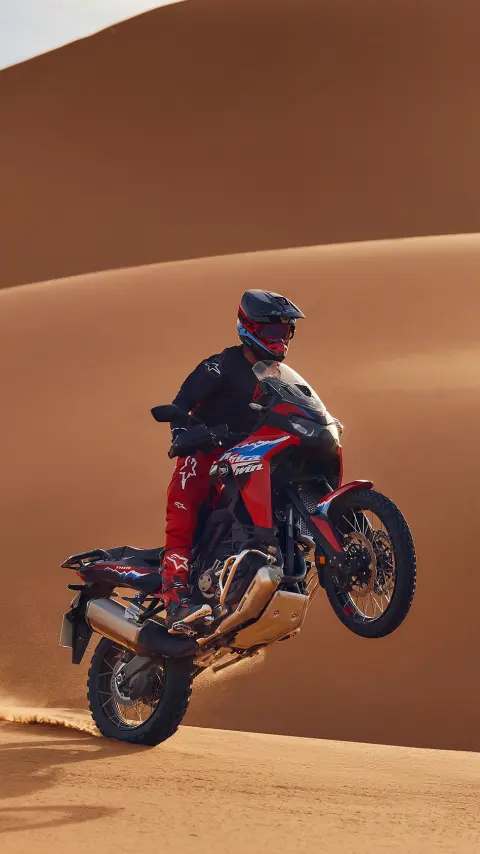 Model na motocyklu CRF1100L Africa Twin w pustynnym otoczeniu.