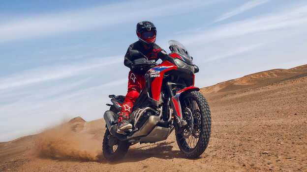 Model na motocyklu CRF1100L Africa Twin w pustynnym otoczeniu.
