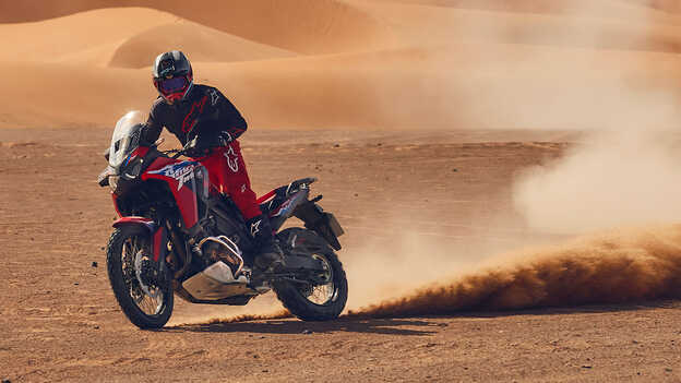 Model jadący po pustyni na motocyklu CRF1100L Africa Twin.