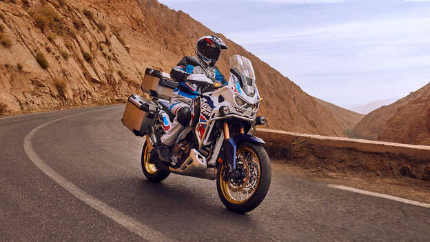 Motocyklista na ustawionej przodem Hondzie CRF1100 Africa Twin Adventure Sports na pustyni.
