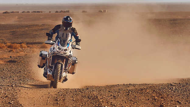 Motocyklista patrzący w przód na Hondzie CRF1100 Africa Twin Adventure Sports na pustyni.
