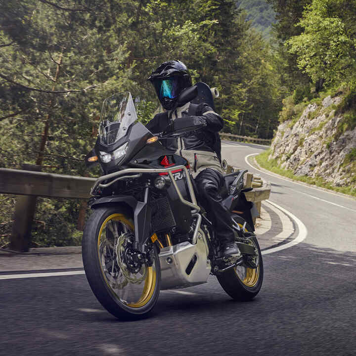 Model jadący na motocyklu XL750 Transalp w górskiej scenerii.