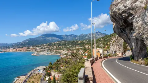 Malownicza droga pod błękitnym niebem wzdłuż wybrzeża Morza Śródziemnego na granicy francusko-włoskiej.