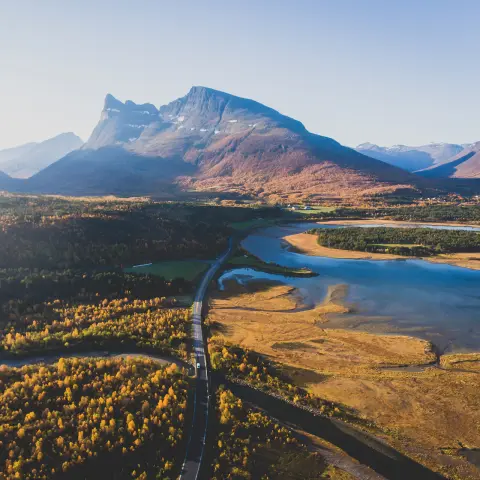 Klasyczny norweski letni górski krajobraz z drogą, majestatycznymi szczytami, fiordem i błękitnym niebem, północna Norwegia, okręg Finnmark, nakręcony z drona