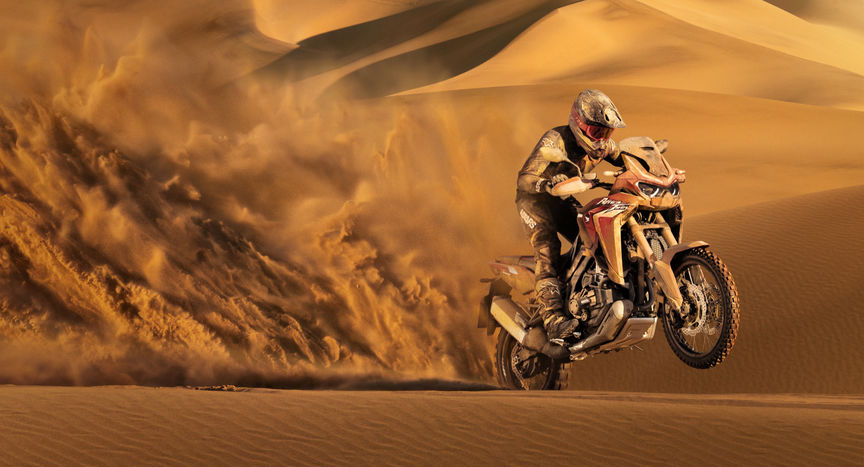 Honda Africa Twin - widok przedstawiający motocykl jadący po piachu z przedniej perspektywy