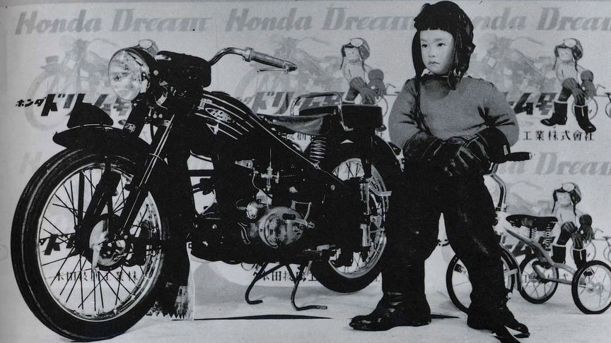 Honda vintage motorcycle three quarter front view and young rider standing.