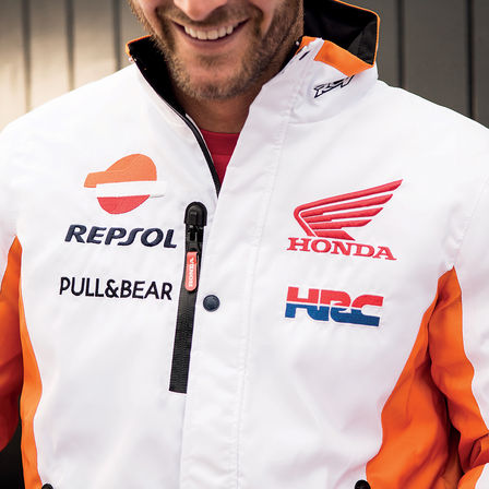Uśmiechnięty mężczyzna ubrany w wyścigowy sweter Hondy.