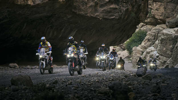 Kierowcy na motocyklach Africa Twin pokonujący górską przełęcz.
