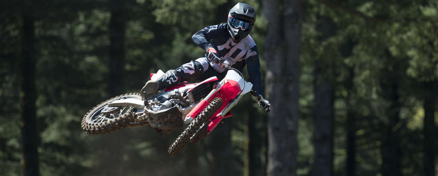 Widok z przodu na motocykl CRF450R wykonujący skok, z kierowcą.