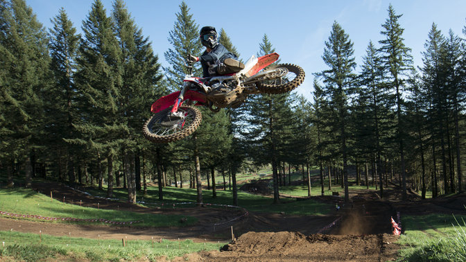 Honda CRF450R wykonująca skok, z kierowcą. Na torze motocrossowym.