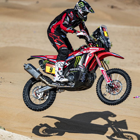 Kierowca Hondy w rajdzie Dakar na motocyklu w otoczeniu pustyni.