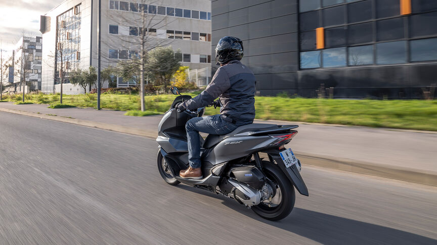 Honda PCX125 - Dynamiczne ujęcie z tyłu z boku z kierowcą na siedzeniu