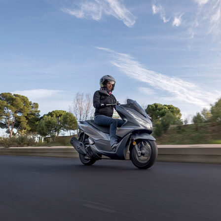 Widok z przodu z boku na Hondę PCX125 jadącą po drodze