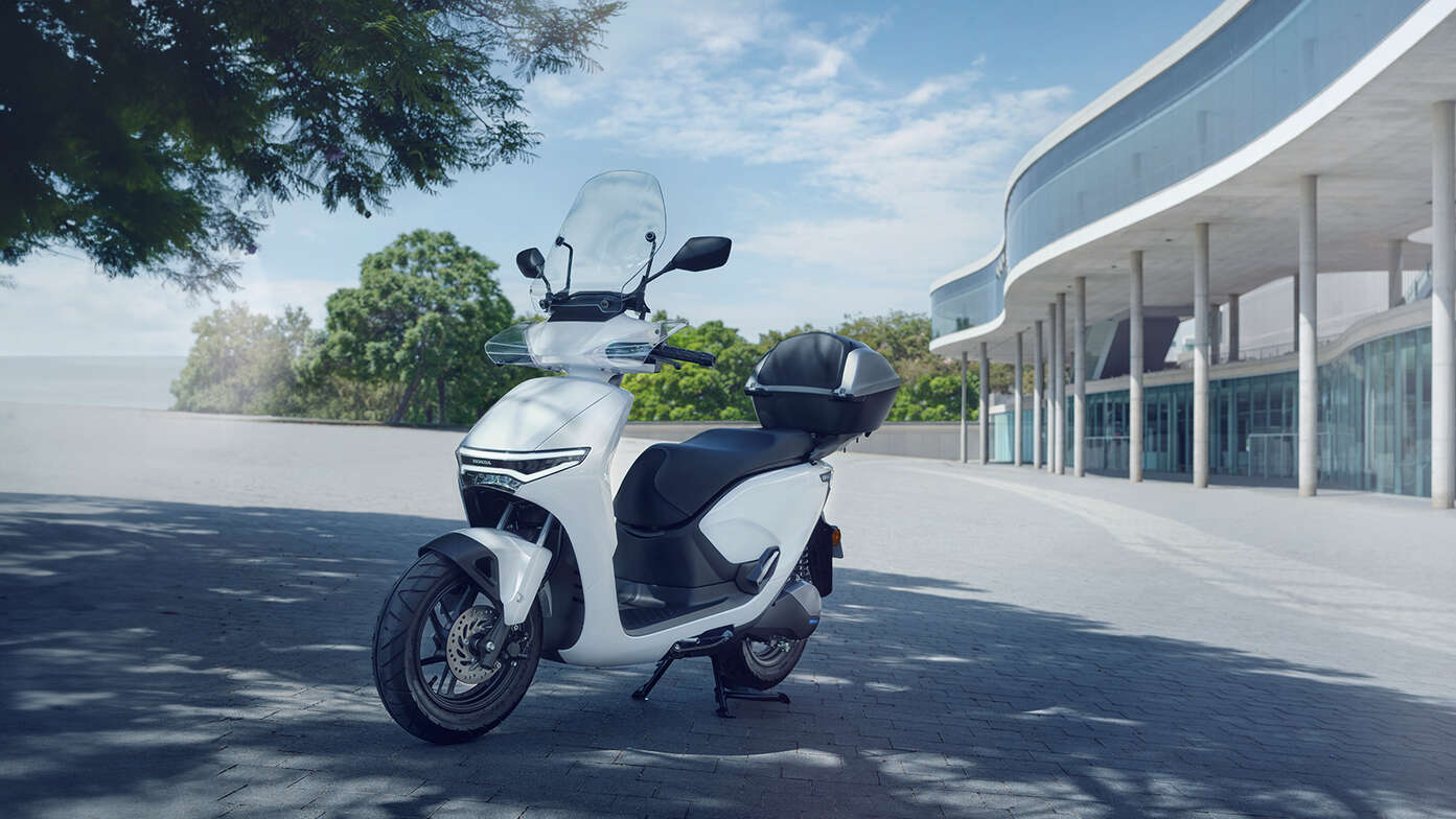 Motocykl Honda CUV e dumnie prezentujący swój ekran, zaparkowany w mieście.