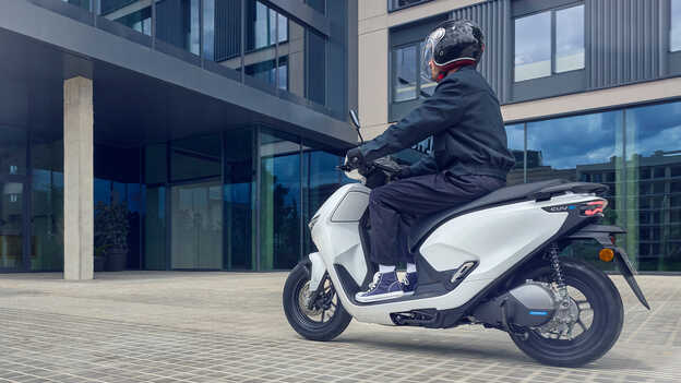 Model jadący motocyklem Honda CUV e i demonstrujący działanie asystenta cofania.