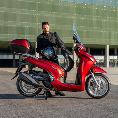 Honda SH350i, człowiek stojący obok skutera, widok z tyłu, czerwony motocykl