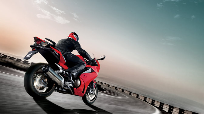 Honda SH Mode – czarny skuter z kierowcą z przedniej perspektywy. Skierowany w prawo (na drodze).