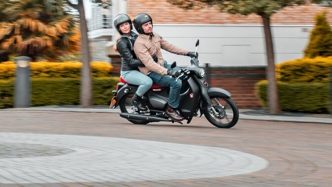 Honda Monkey oparta na bocznej stopce, na drodze z kierowcą