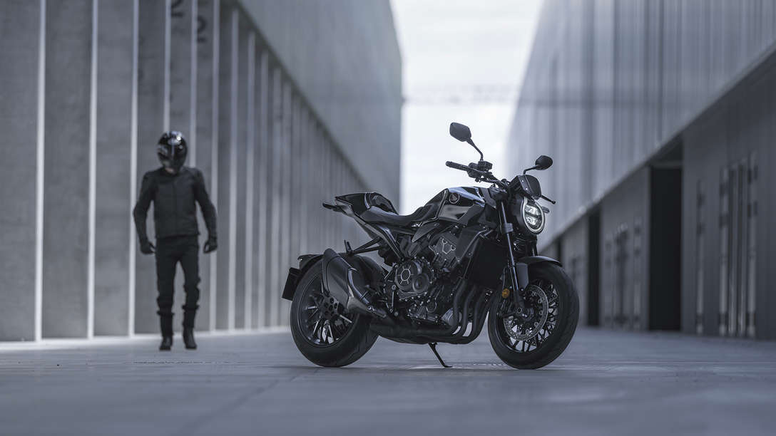 Honda CB1000R Black Edition — mężczyzna stojący obok motocykla na ulicy między budynkami