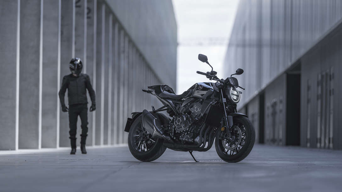 Honda CB1000R Black Edition &mdash; mężczyzna stojący obok motocykla na ulicy między budynkami